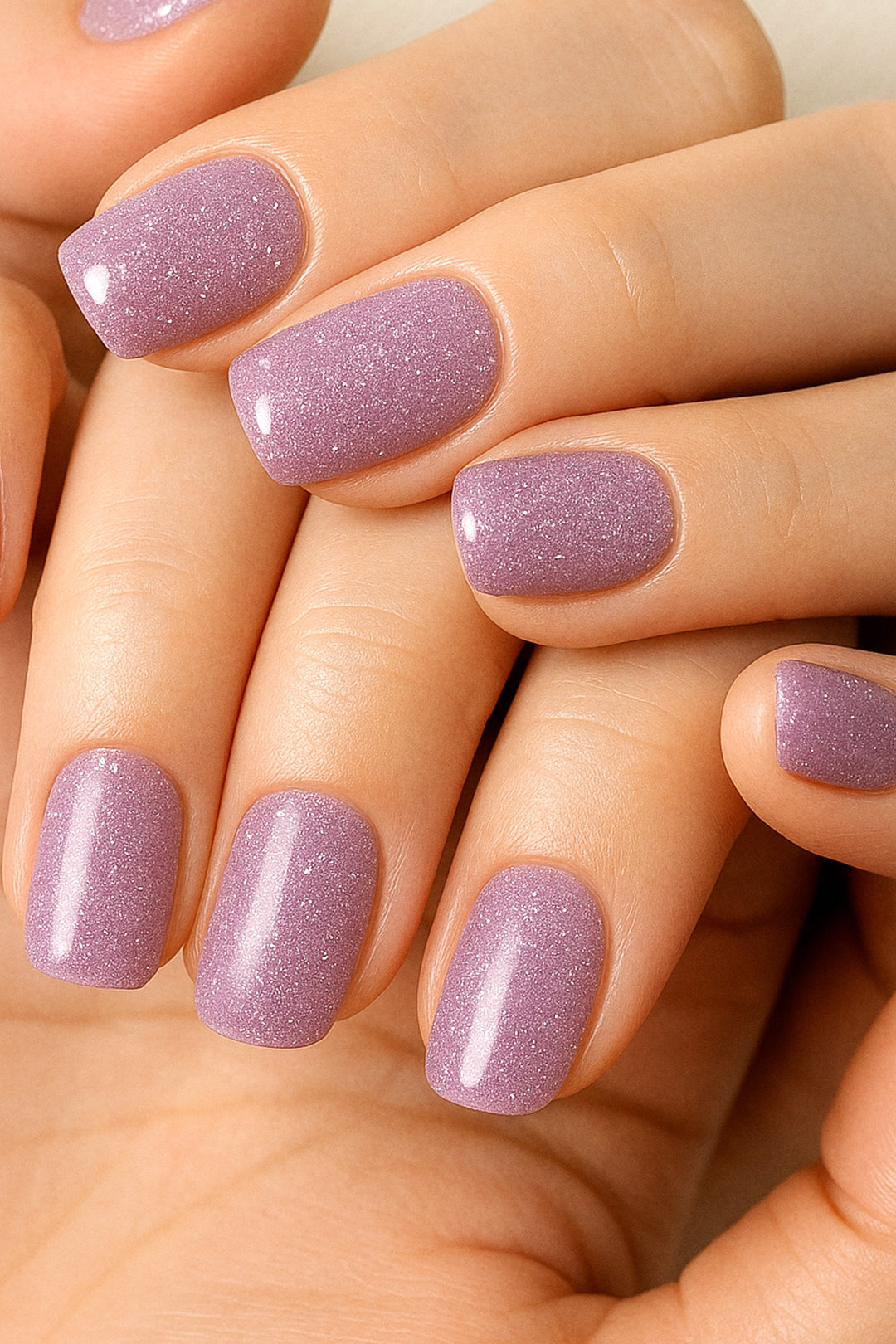 A model’s hand wearing Lilac Dust simple glitter nail stickies, showcasing the pastel lavender shade with delicate sparkles, highlighting its soft glossy shine and adding a chic, minimal yet elegant nail art look – Muselot.