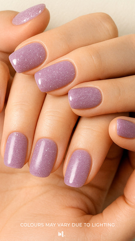A model’s hand wearing Lilac Dust simple glitter nail stickies, showcasing the pastel lavender shade with delicate sparkles, highlighting its soft glossy shine and adding a chic, minimal yet elegant nail art look – Muselot.