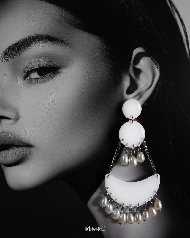 A woman wearing the Mahtab chandbali earrings, highlighting their white crescent-shaped design adorned with pearl drops and silver chains, showcasing graceful sophistication and handcrafted elegance — Muselot.