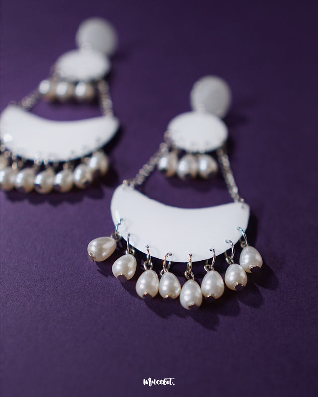 Mahtab pearl chandbali earrings featuring a glossy white crescent base with silver chains and teardrop pearls, showcasing their handcrafted elegance against a deep purple background — Muselot.