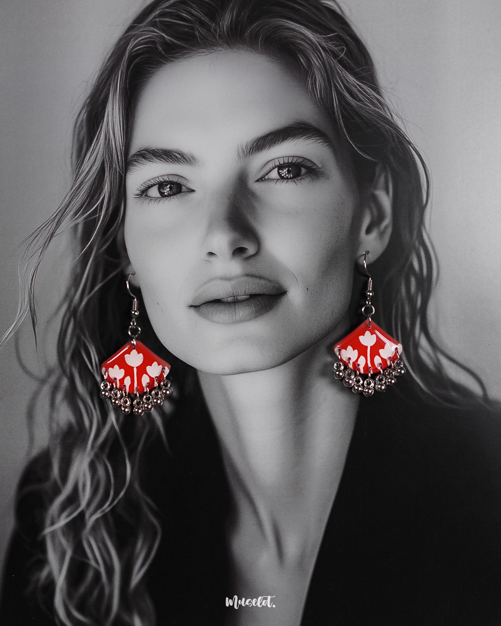 A model styles the Meherbaan red floral earrings with poise, showcasing the vibrant red hand-painted tulip design and silver ghungroo detailing that lend a charming ethnic flair — Muselot.