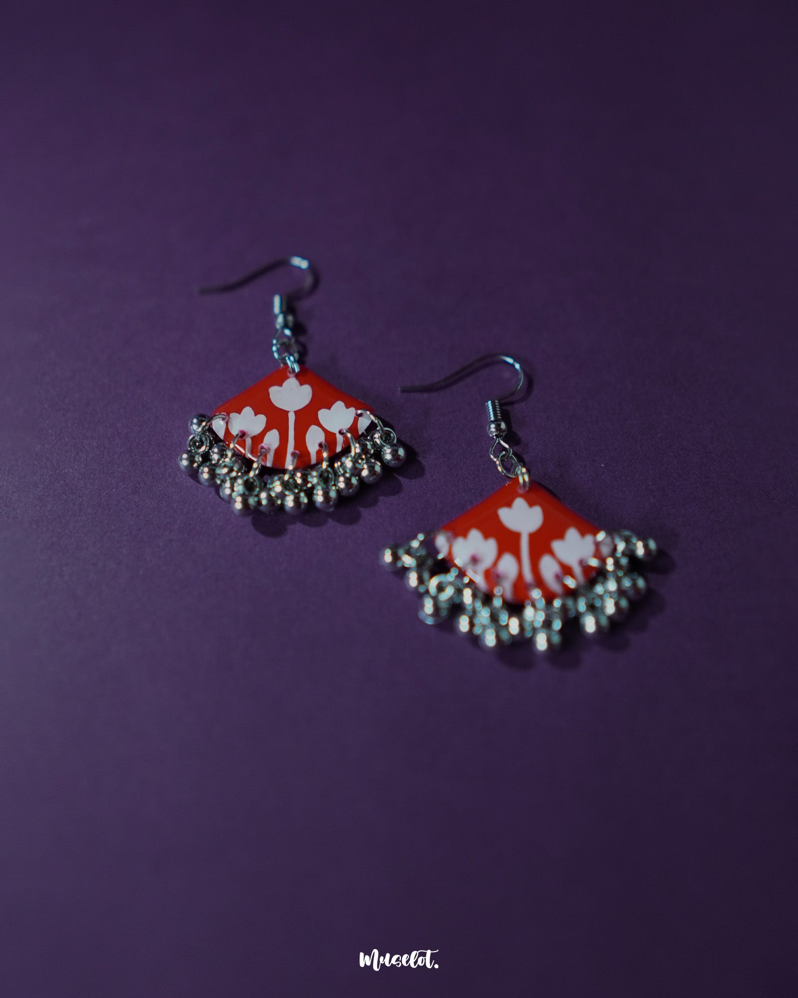 A Meherbaan red floral hook earrings, showcasing their bold red tulip design with silver ghungroos, highlighting the handmade charm and festive elegance — Muselot.