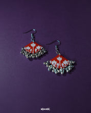 A Meherbaan red floral hook earrings, showcasing their bold red tulip design with silver ghungroos, highlighting the handmade charm and festive elegance — Muselot.