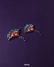 Meherbaan red floral hook earrings placed flat against a soft-toned background, showcasing their blooming red floral design with detailing and graceful hook finish — Muselot.