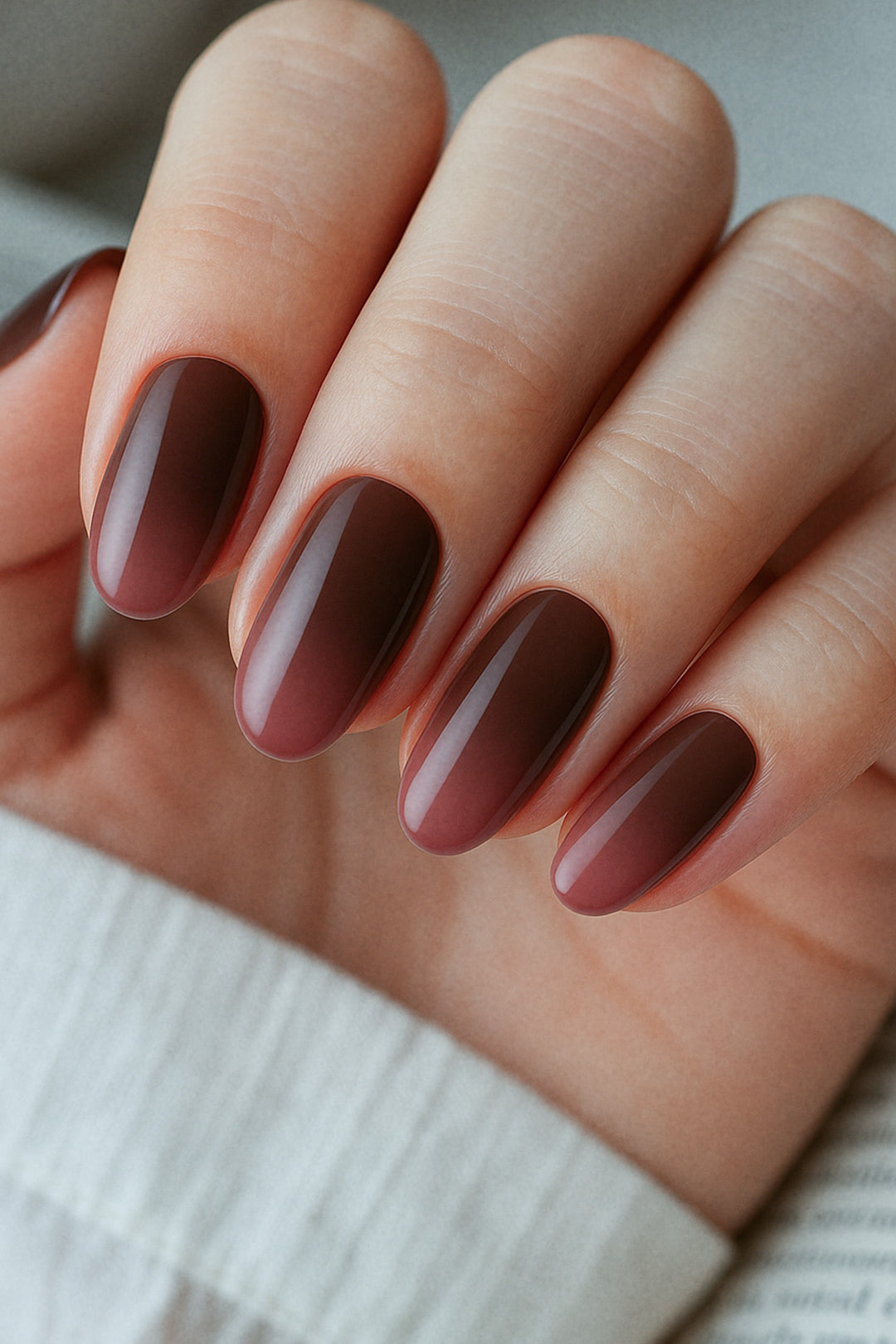 A detailed close-up of a model’s finger's wearing Melted Cocoa brown ombre nail polish stickies, showcasing the smooth gradient that blends from a soft milk-chocolate brown into a deep cocoa shade, highlighting the glossy texture and elegant salon-style ombre finish – Muselot.