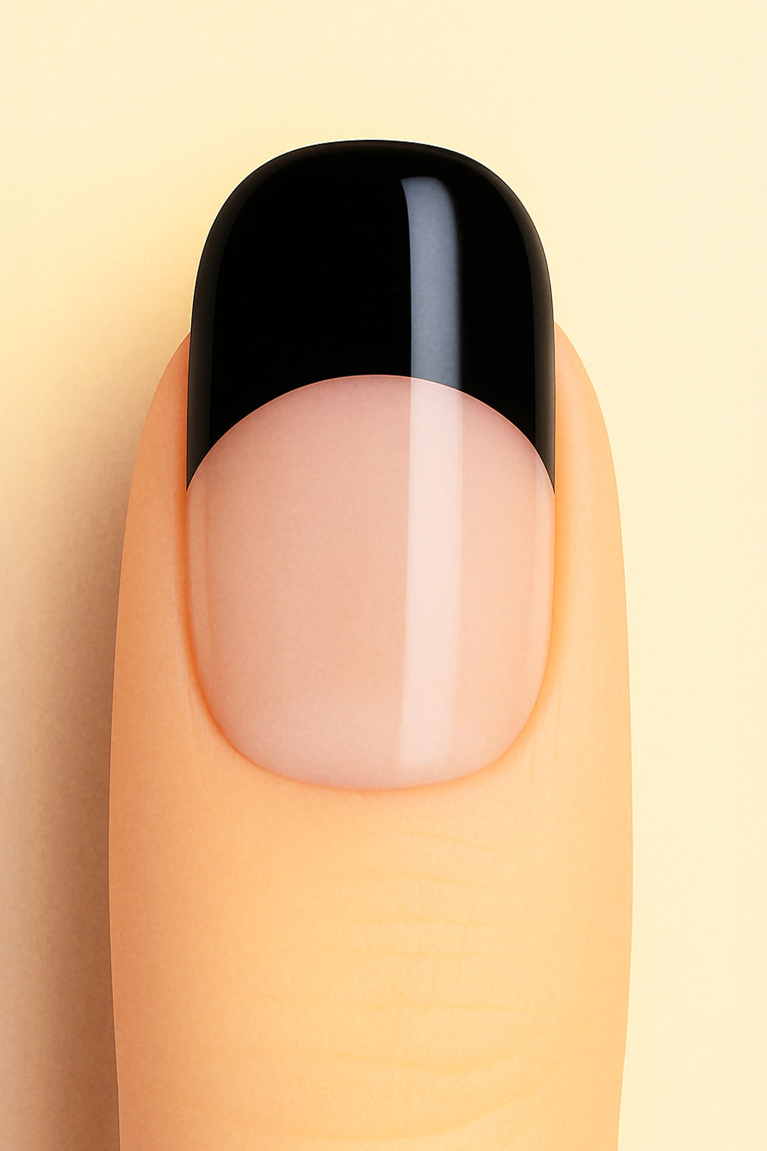 A close-up view of a finger wearing Midnight Tiara French Tip nail stickies, featuring a sleek black tip over a glossy nude base. The design highlights the timeless elegance of the French manicure with a bold, modern twist, giving a chic and sophisticated finish – Muselot.