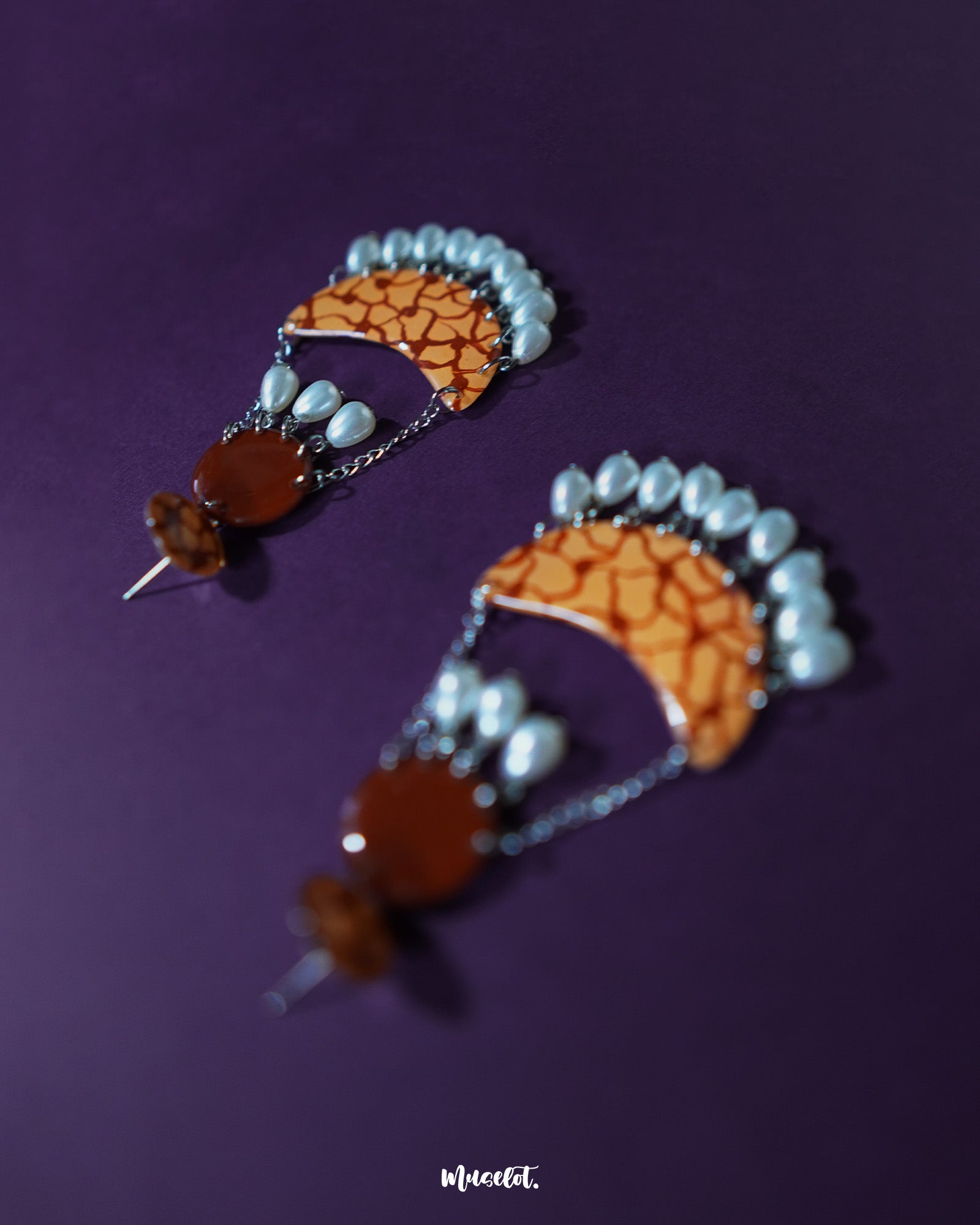 Mittika chandbali earrings captured in a front-facing view, highlighting the intricate crackle pattern in earthy orange tones and glistening pearl drops that dangle elegantly from silver chains — Muselot.