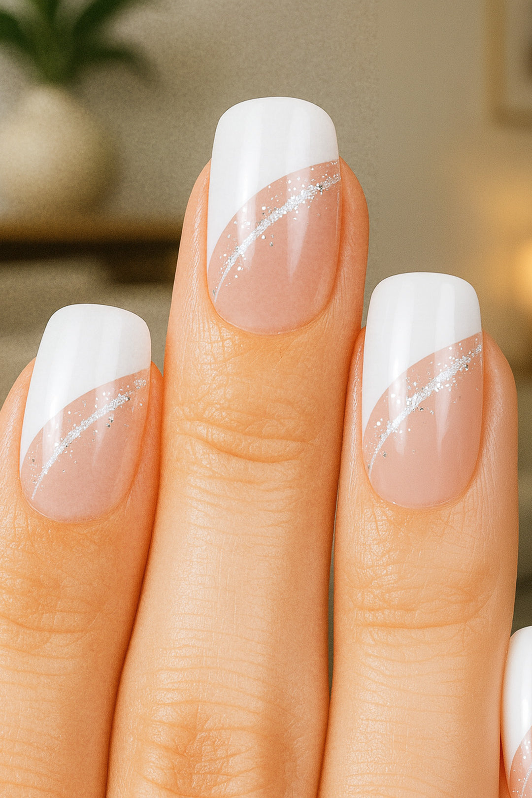 A model’s hand showcasing the Moonlit Wave White French Nail Art from Muselot. The nails feature a modern diagonal French tip in crisp white, highlighted with a fine silver glitter accent line, contrasted against a glossy nude base. The elegant design gives a polished, sophisticated finish perfect for everyday chic or special occasions.