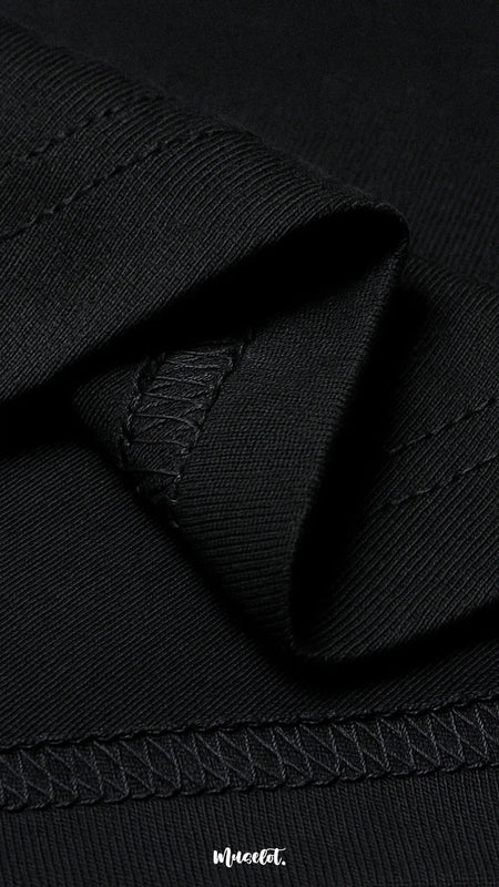 A zoomed-in view of the unisex black t-shirt, highlighting the double seam stitching for added strength, lasting durability, and a neat polished finish—Muselot