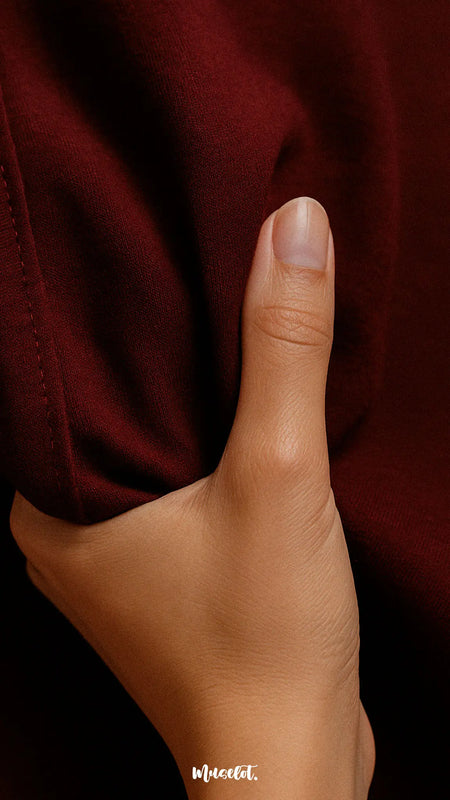 Close-up view of the maroon T-shirt from Muselot’s soft cotton combo, gently touched by hand to showcase its smooth, breathable texture and premium comfort,highlighting the tactile quality and everyday ease of wear — Muselot.