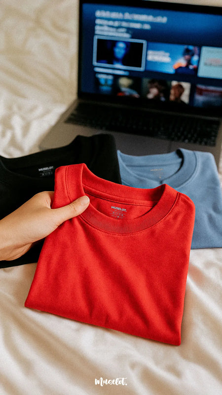 A combo of three unisex cotton T-shirts in scarlet red, dusty blue, and jet black, neatly laid on a neutral-toned fabric that brings out the richness of each color, highlighting their smooth texture, relaxed fit, and bold aesthetic perfect for everyday comfort and casual binge days — Muselot.