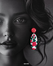 A close-up of a woman wearing the Nargis handmade floral drop earrings, highlighting the vivid pink and green floral design on white ovals, showcasing the vibrant charm and hand-painted detailing — Muselot.