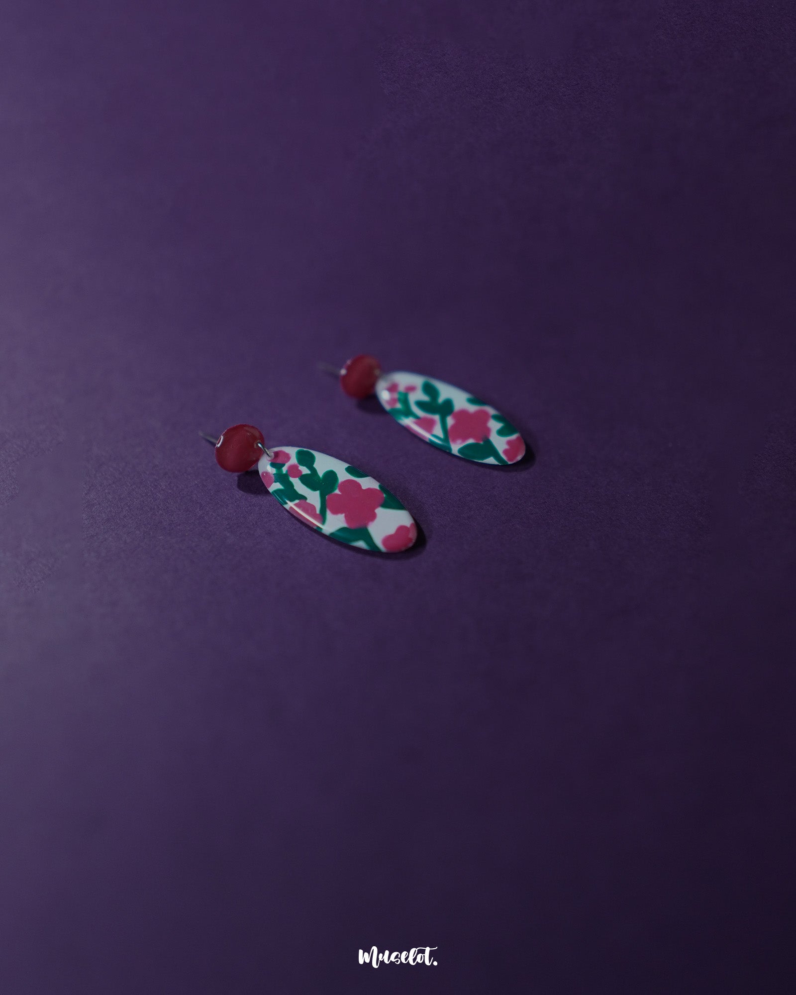 Side view of the Nargis pink floral drop earrings placed against a soft background, showcasing the curved floral design and elegant color contrast that adds charm to handmade jewelry — Muselot.