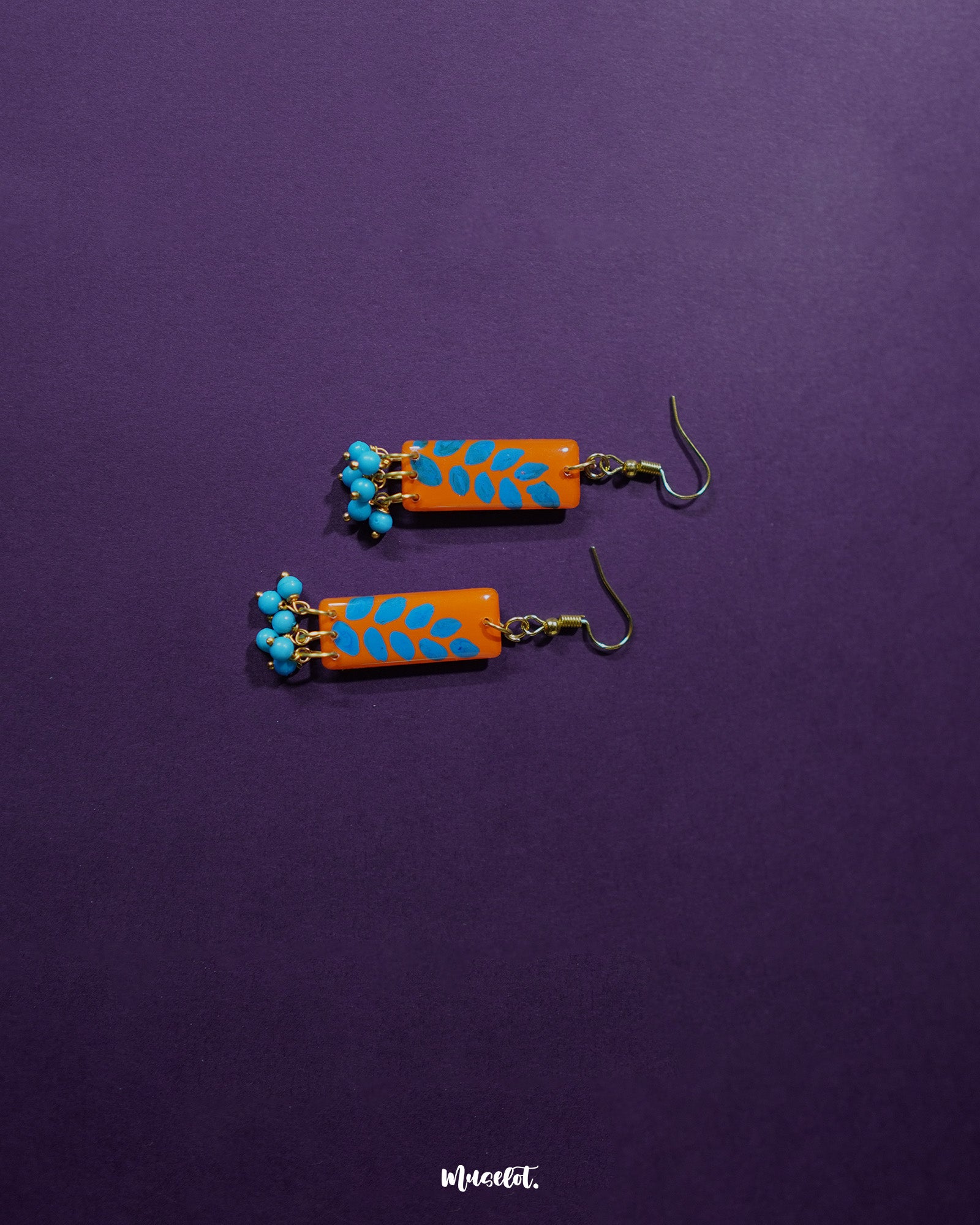 A Narmshaam handmade hook earrings placed against a soft fabric background, highlighting the intricate handwoven pattern and the earthy tones that lend a calm, artistic charm to everyday styling — Muselot.