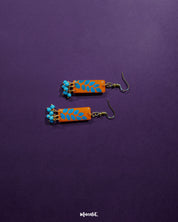 A Narmshaam handmade hook earrings placed against a soft fabric background, highlighting the intricate handwoven pattern and the earthy tones that lend a calm, artistic charm to everyday styling — Muselot.