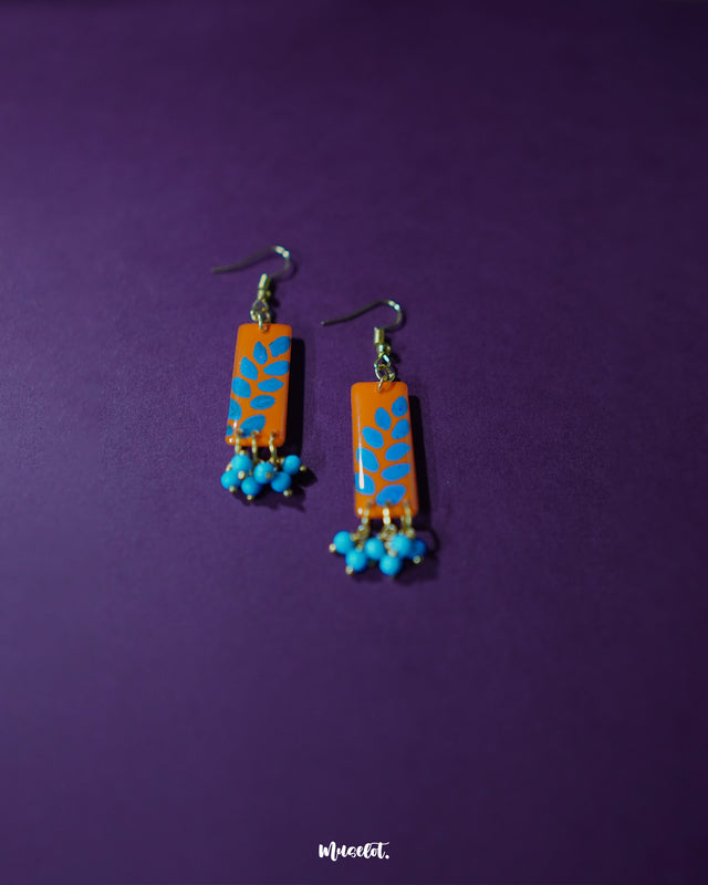 Narmshaam handmade hook earrings displayed against a vibrant purple background, highlighting their earthy color palette and delicate threadwork that reflect artisanal elegance and timeless charm — Muselot.