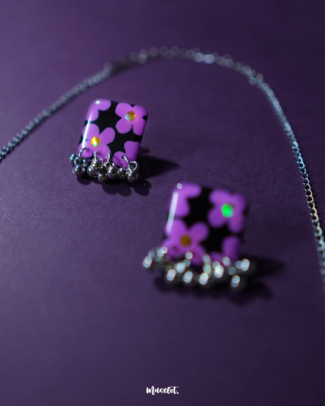 A simple and elegant purple necklace set with lavender floral details, set against a deep purple background, showcasing delicate craftsmanship — Muselot.