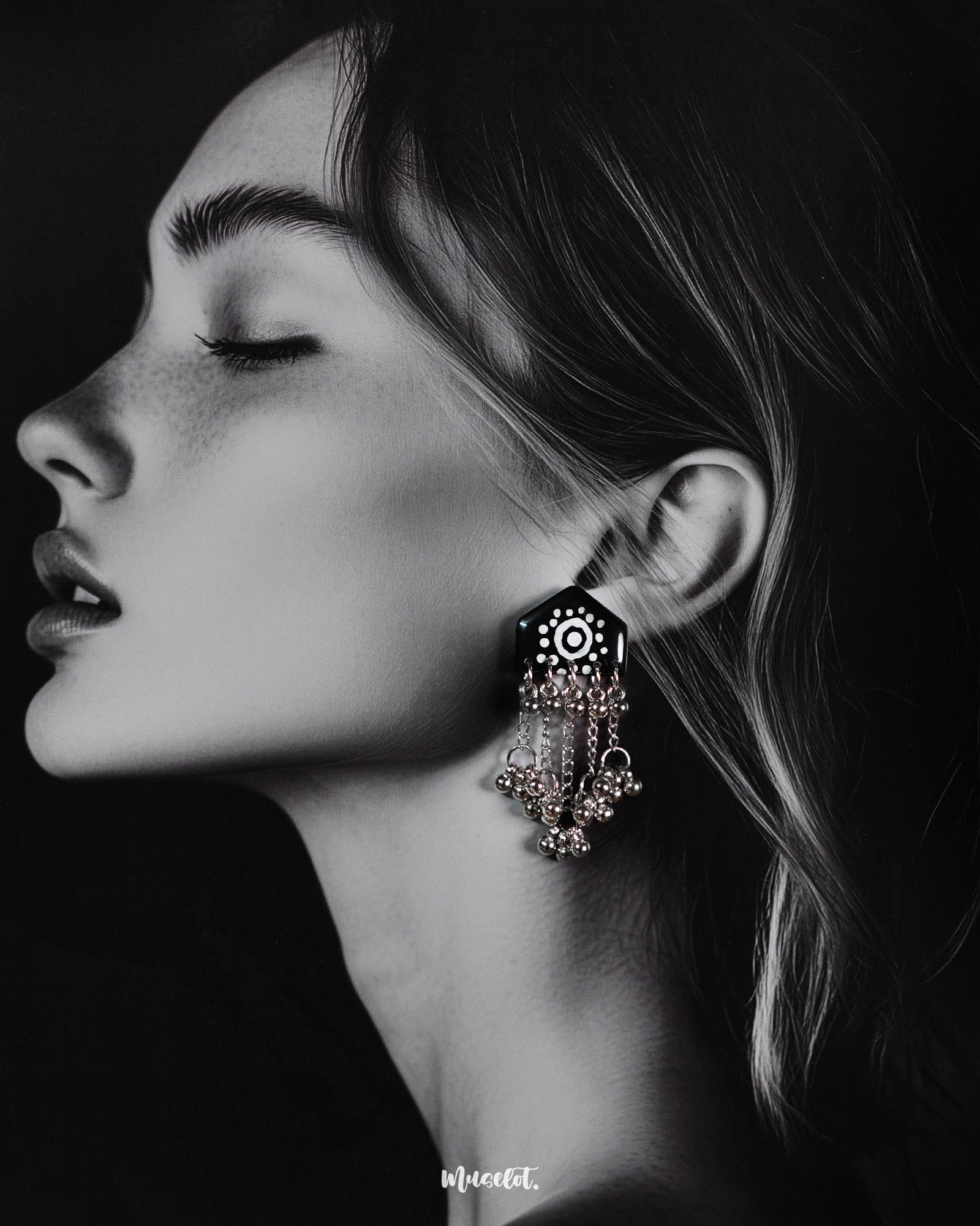Model wearing Nazafar black handcrafted earrings, featuring white painted motifs and layered silver ghungroo chains for a striking traditional look – Muselot.