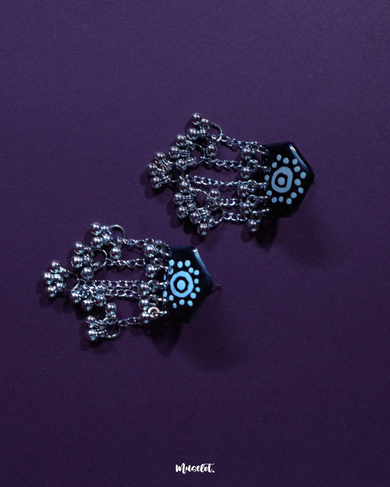 Nazafar black jhumkas captured at an angle, showcasing the bold hand-painted white patterns while highlighting the oxidized silver dome and artisanal charm – Muselot.