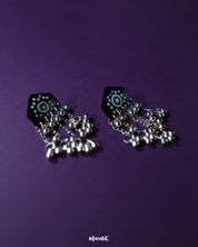 Nazafar black jhumkas presented front-facing, showcasing vivid white motif detailing while highlighting the antique silver dome and handcrafted cultural elegance – Muselot.