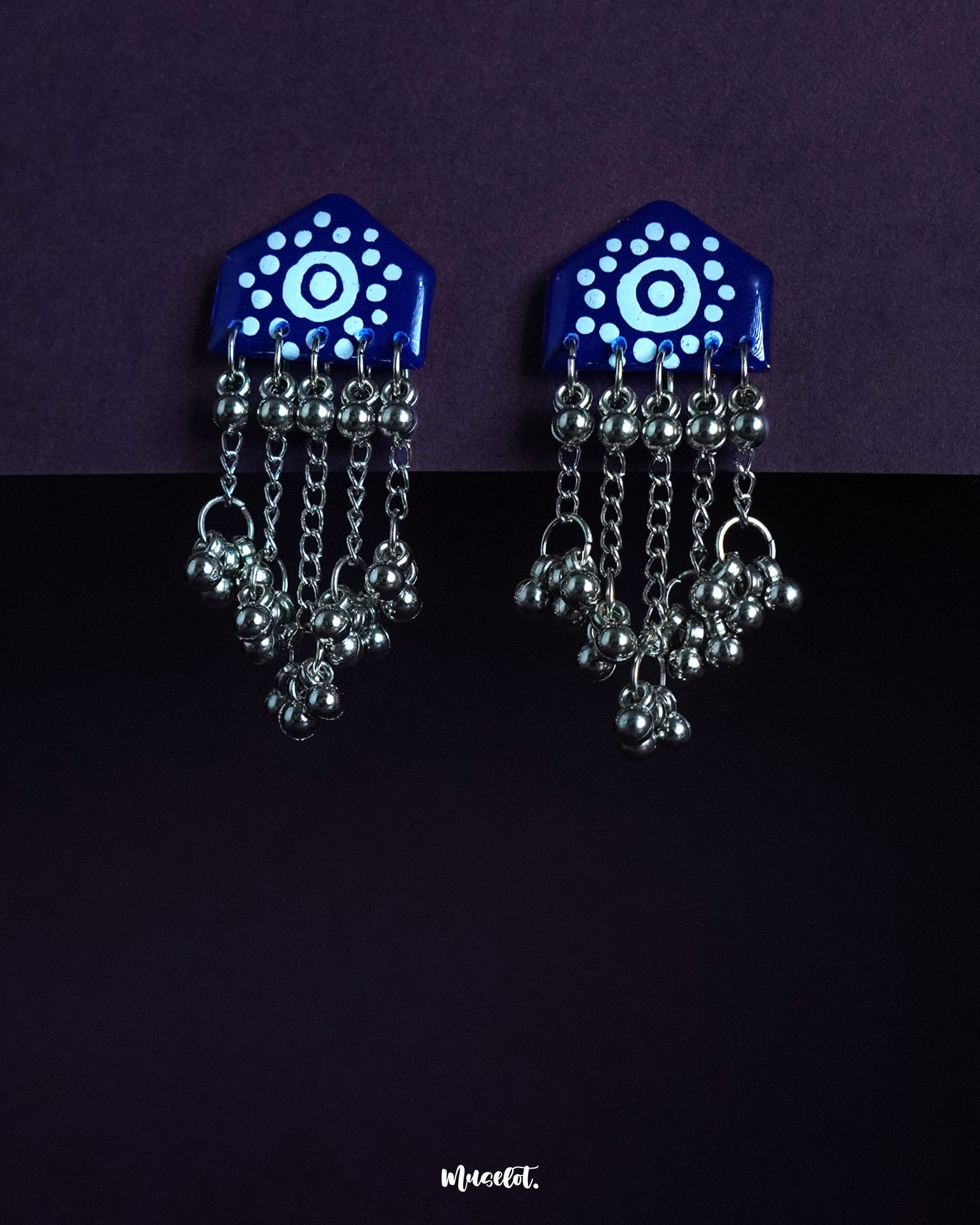 Nazafar dark blue handcrafted earrings with white circular motifs and cascading silver ghungroo chains, displayed against a simple backdrop – Muselot.