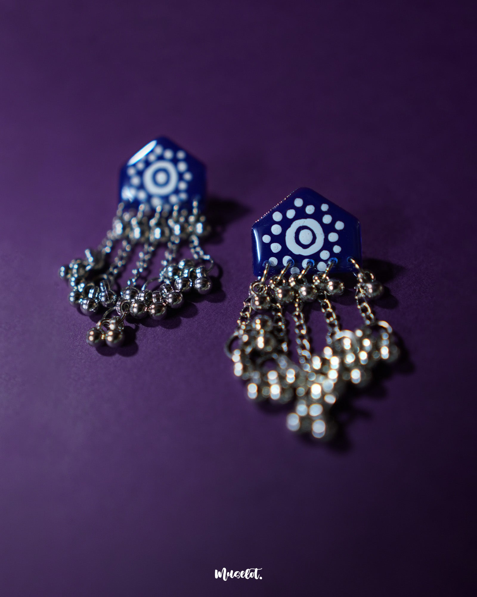Nazafar dark blue jhumkas displayed on a plain backdrop, showcasing bold white motif accents while highlighting the oxidized silver dome and traditional handcrafted charm – Muselot.