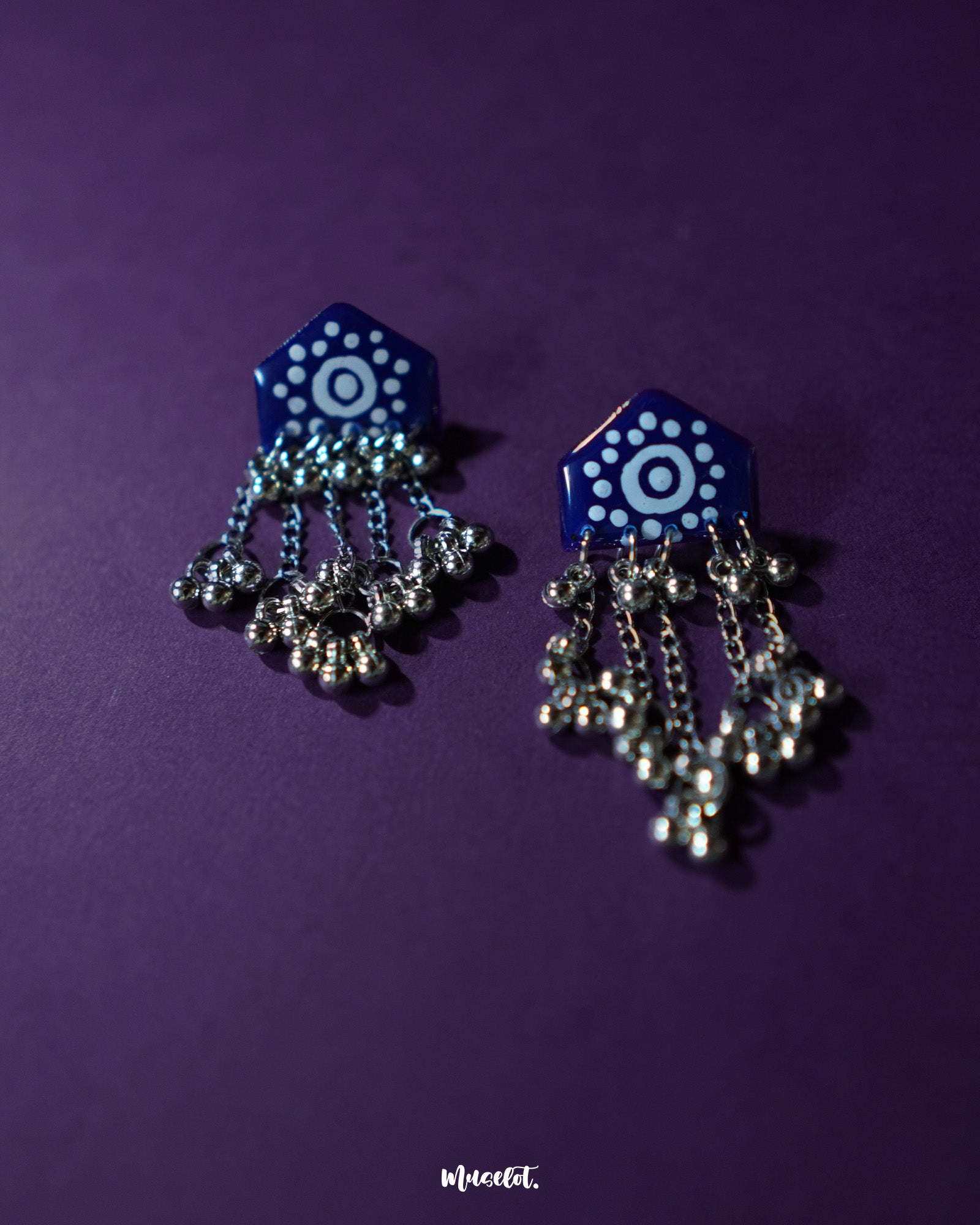 Nazafar dark blue jhumkas in a front view, showcasing the vivid white painted motifs while highlighting the antique silver dome and ethnic elegance – Muselot.