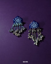 Nazafar dark blue jhumkas in a front view, showcasing the vivid white painted motifs while highlighting the antique silver dome and ethnic elegance – Muselot.