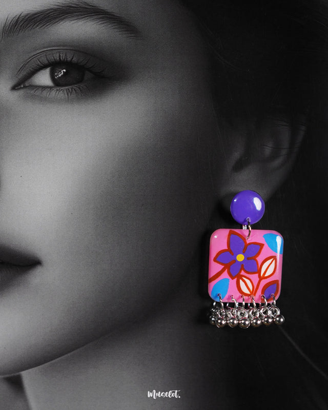  a model wearing Nazmira floral stud earrings, featuring intricate floral patterns and warm, pink tones that add a touch of bohemian elegance to the look — Muselot.