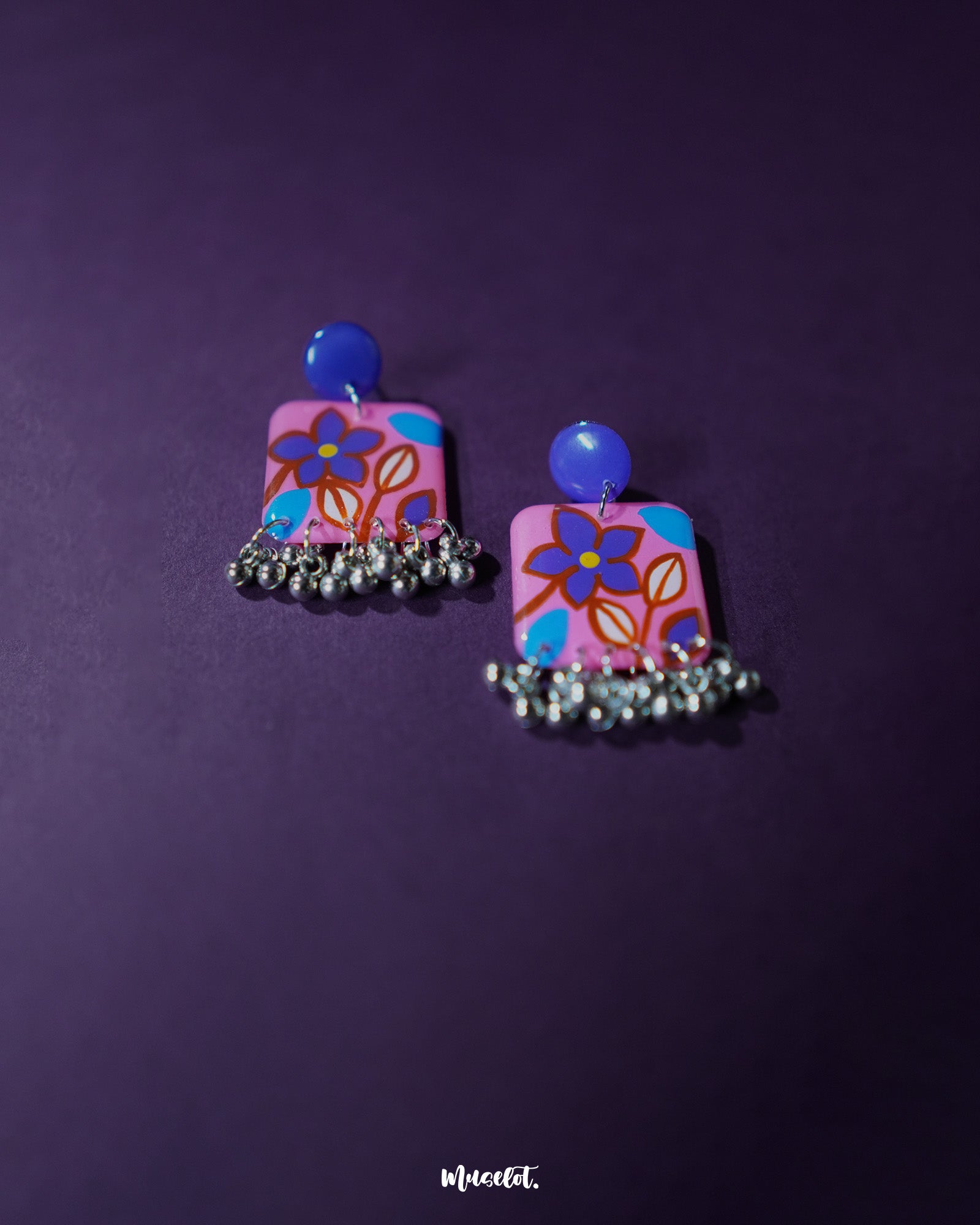 Nazmira handmade floral stud drop earrings, set against a deep purple backdrop, with intricate floral craftsmanship and a graceful drop design that adds a touch of boho elegance to any look — Muselot.