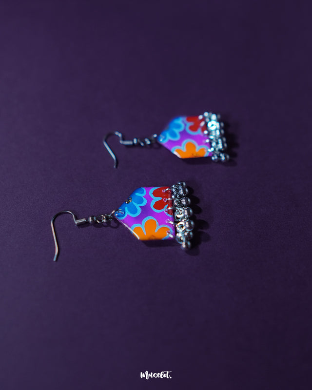Detailed view of Nazrana multicolour floral earrings, focusing on the bold hand-painted motifs and traditional ghungroo drops against a simple backdrop – Muselot.