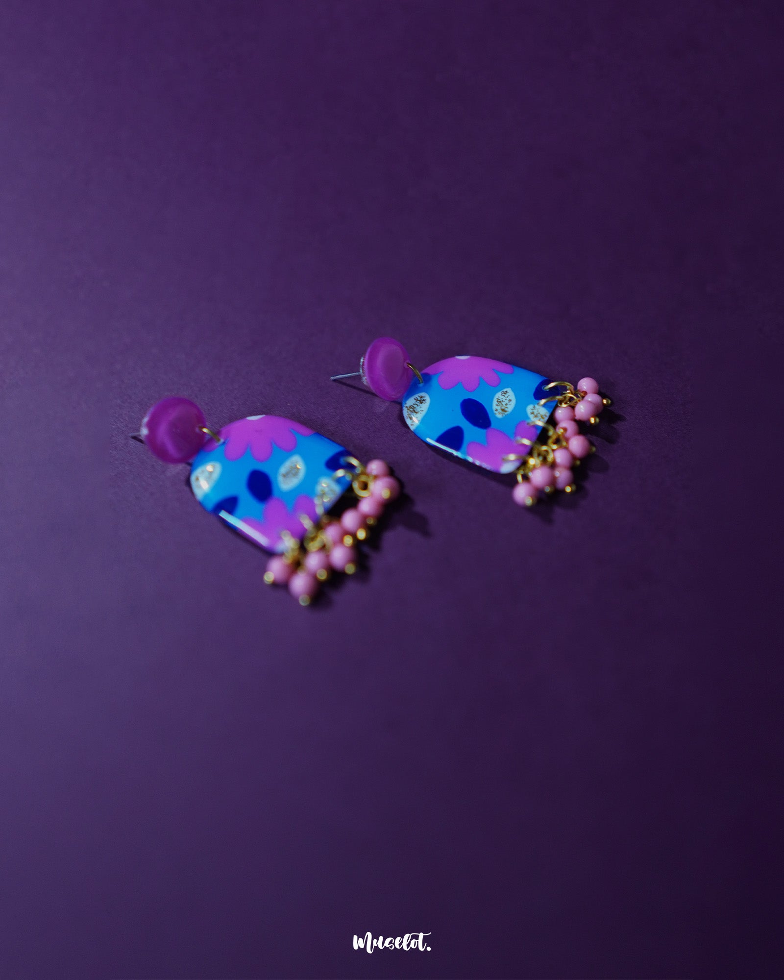The Neelzair purple floral earrings, showcasing the vibrant blend of blue, pink, and gold tones that highlight their handcrafted elegance and playful beaded fringe — Muselot.