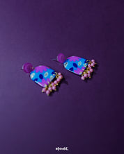 The Neelzair purple floral earrings, showcasing the vibrant blend of blue, pink, and gold tones that highlight their handcrafted elegance and playful beaded fringe — Muselot.