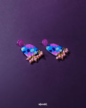 The Neelzair purple floral earrings featuring delicate floral detailing with cascading beadwork, showcasing their handcrafted charm and bohemian elegance — Muselot.