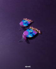 The Neelzair purple floral earrings displayed from a side angle, showcasing the vibrant floral accents and lightweight handcrafted design that add a charming statement to any look — Muselot.