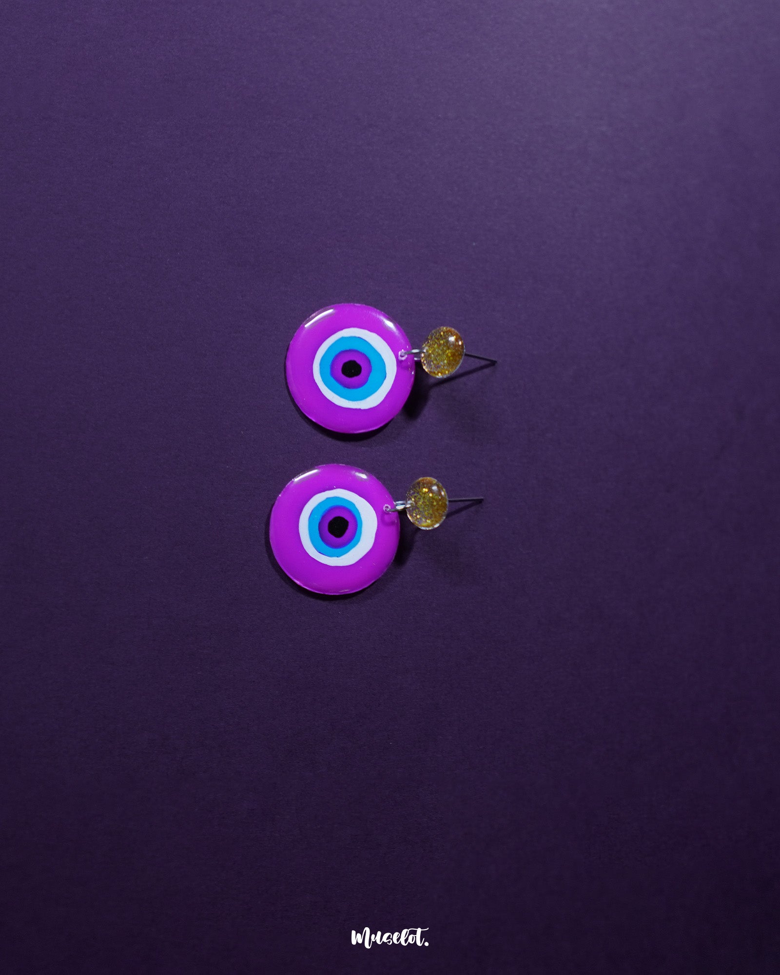 Nigaahbaan evil eye stud earrings featuring a striking deep blue center surrounded by pink, white, and purple concentric rings—playfully capturing the essence of protection with a vibrant handmade twist – Muselot.