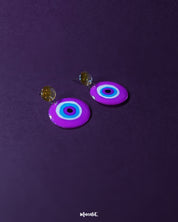 A clean front view of the Nigaahbaan evil eye stud earrings, featuring a circular, colorful design with a striking blue center that draws attention—perfect for subtle yet powerful everyday style – Muselot.