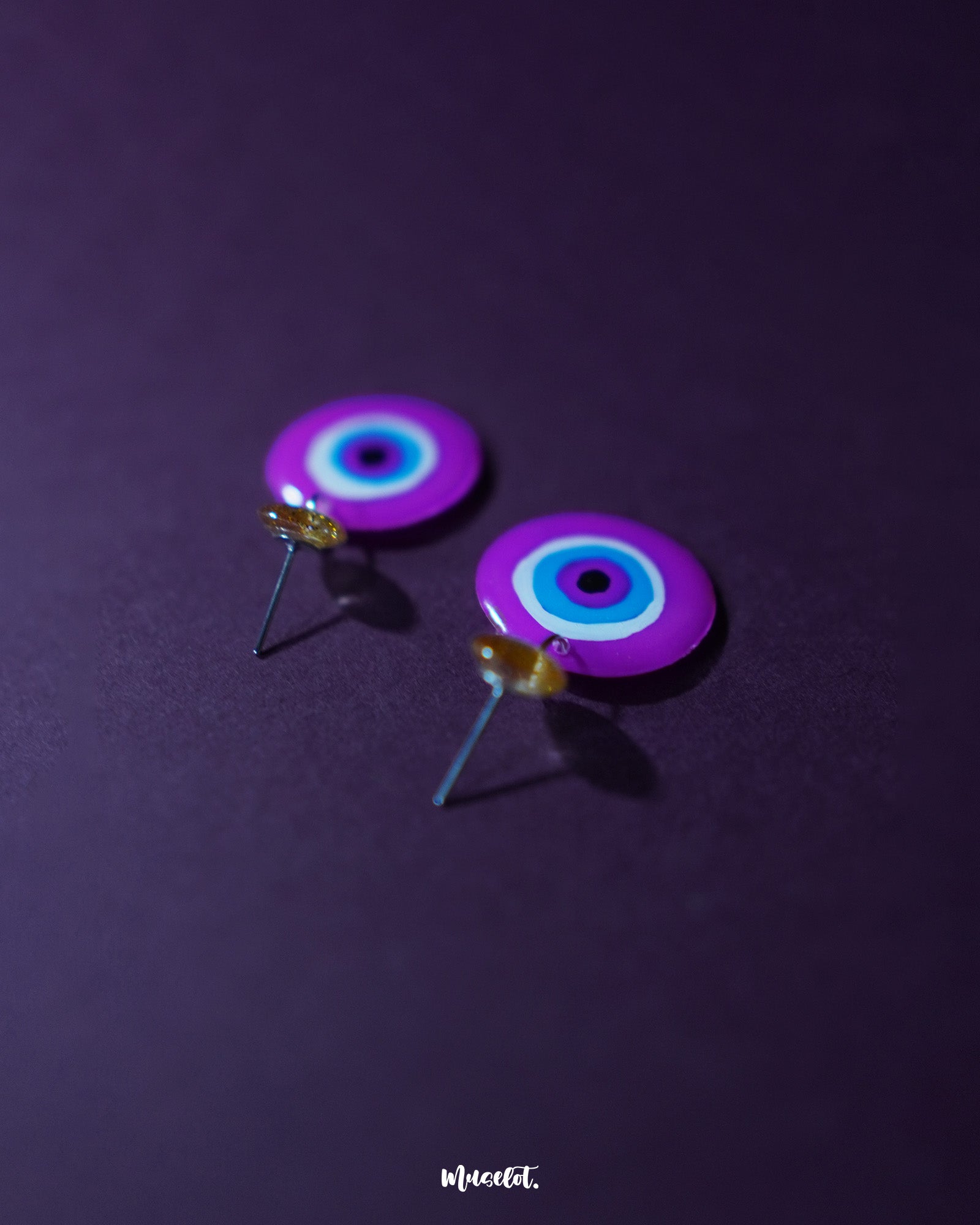 A vivid close-up of the Nigaahbaan evil eye stud earrings, highlighting the glossy blue center framed by soft pink and lavender rings—bringing a modern, artistic edge to traditional symbolism – Muselot.