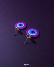 A vivid close-up of the Nigaahbaan evil eye stud earrings, highlighting the glossy blue center framed by soft pink and lavender rings—bringing a modern, artistic edge to traditional symbolism – Muselot.