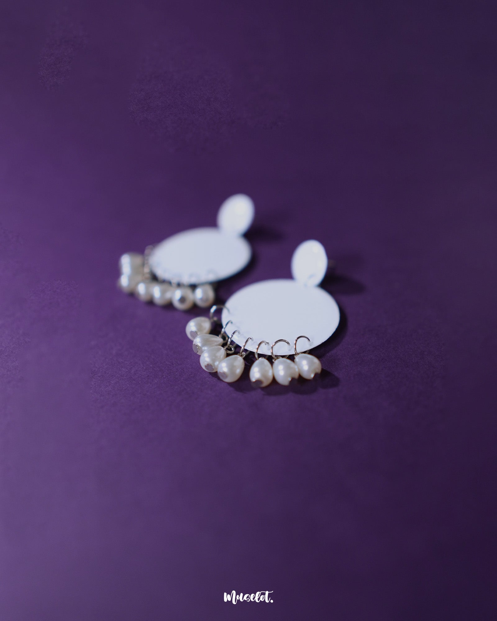 Close-up of Noor white drop earrings featuring delicate pearl-like beads and a crescent-shaped frame, highlighting intricate detailing and showcasing graceful, handcrafted elegance — Muselot.