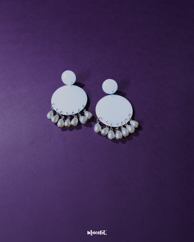A pair of Noor white drop earrings laid flat, showcasing their crescent shape adorned with intricate pearl-like beads and fine metallic detailing that highlights their traditional charm and artisanal craftsmanship — Muselot.