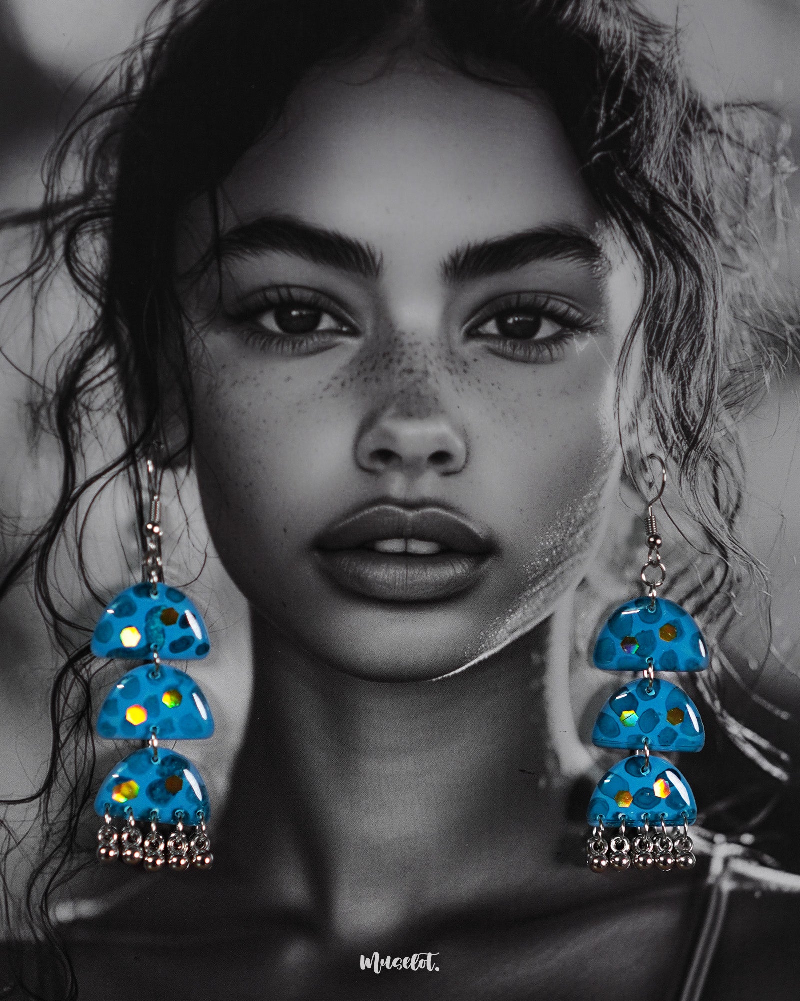 A woman wearing Parvaaz handmade blue drop earrings in a delicate teardrop shape, showcasing the hand-painted floral patterns and highlighting the statement charm and artistic craftsmanship — Muselot.