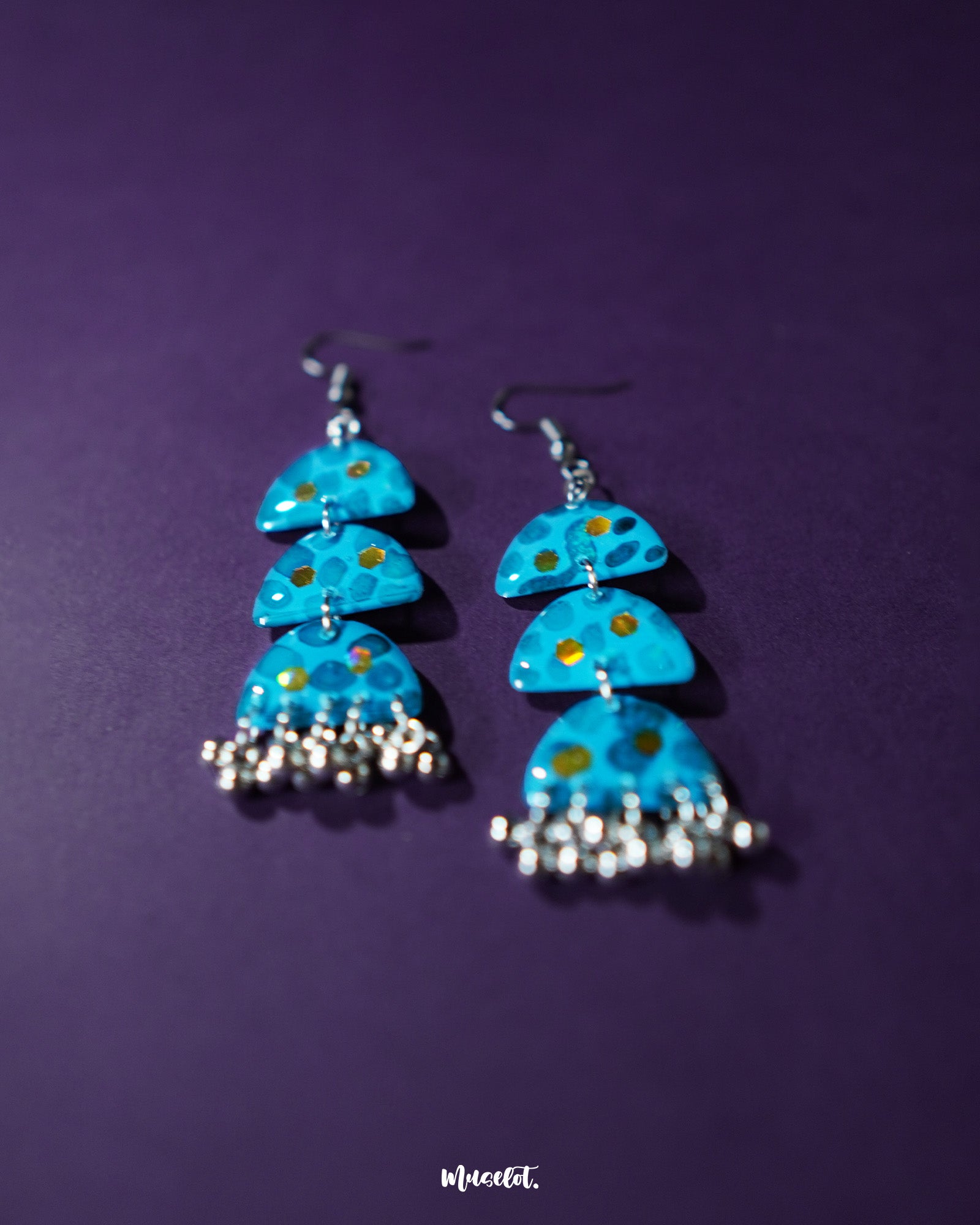 A close-up shot of Parvaaz blue drop earrings, featuring intricate hand-painted floral patterns in shades of blue, highlighting the fine detailing and showcasing their handcrafted charm and elegance — Muselot.