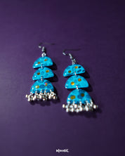 A close-up shot of Parvaaz blue drop earrings, featuring intricate hand-painted floral patterns in shades of blue, highlighting the fine detailing and showcasing their handcrafted charm and elegance — Muselot.