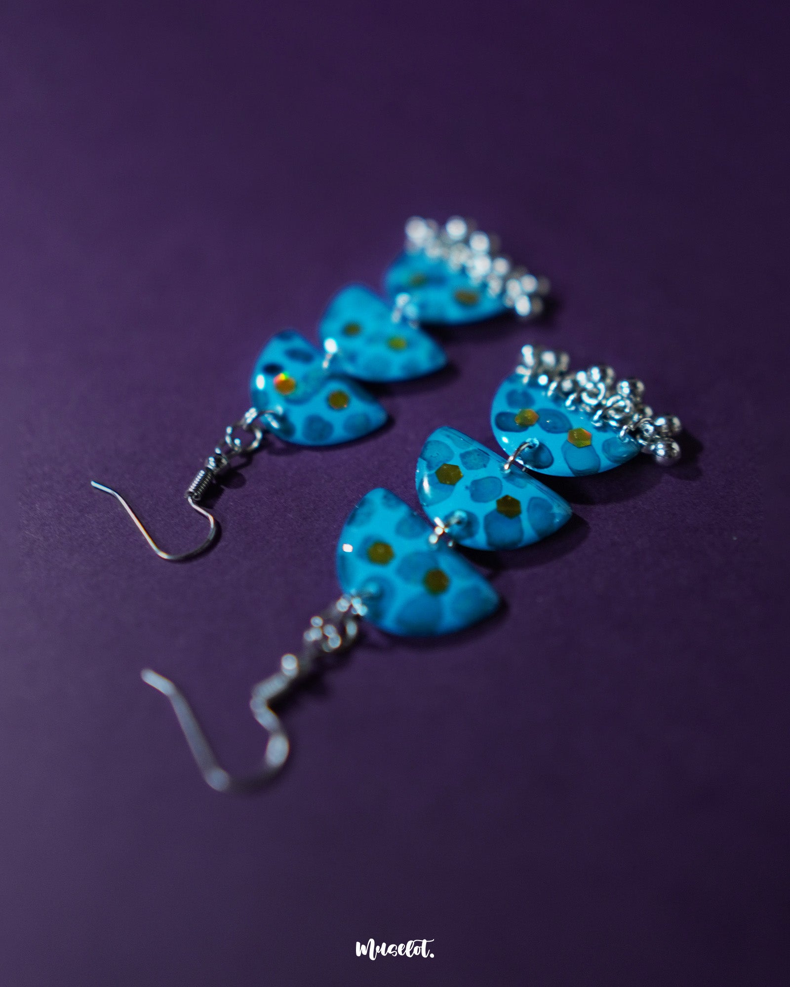 Close-up of Parvaaz blue drop earrings featuring intricately hand-painted floral patterns in shades of blue with delicate leaf accents, highlighting the fine detailing and showcasing the charm of artisanal jewelry — Muselot.