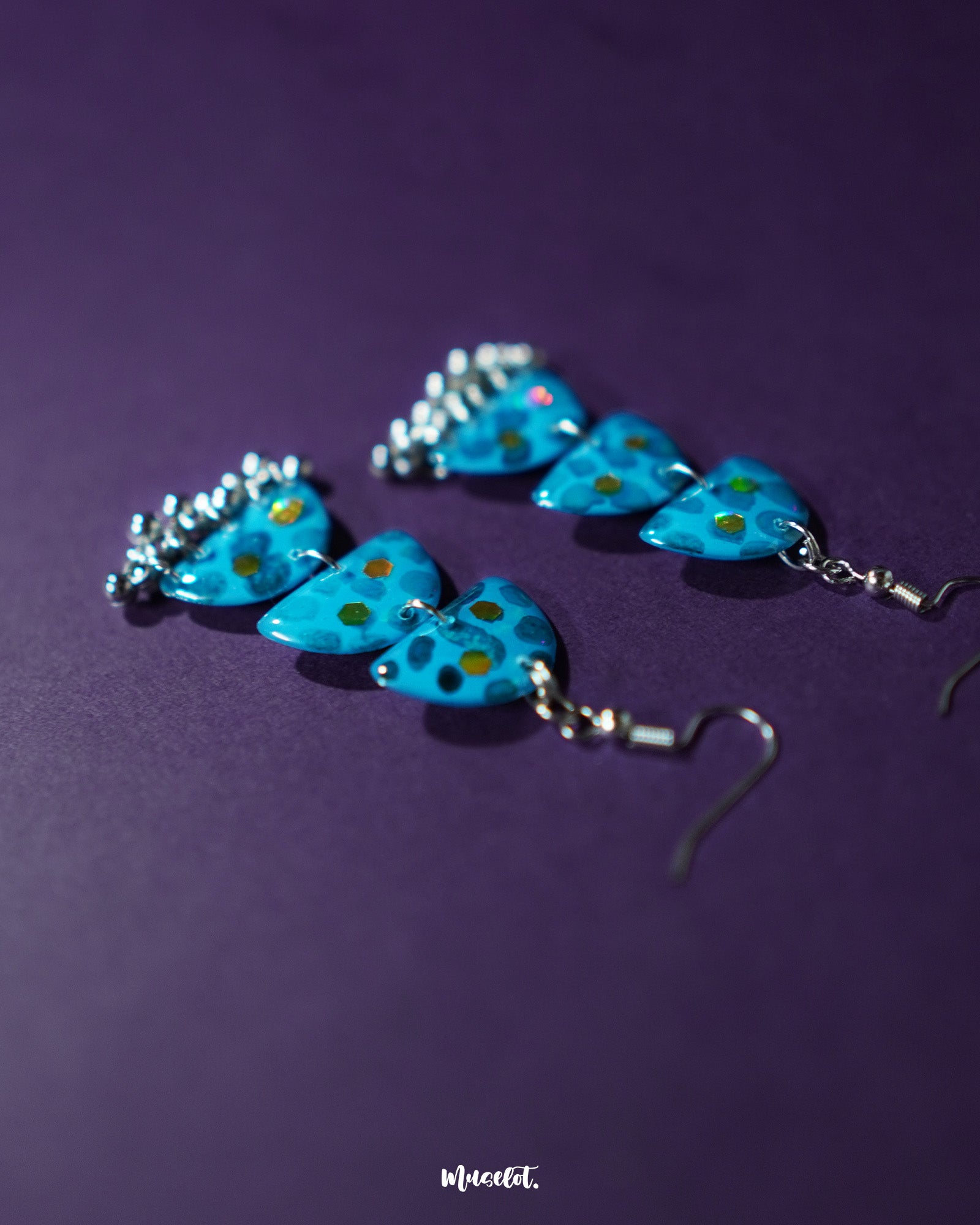 A detailed shot of Parvaaz blue drop earrings, displaying a rich blend of blue floral motifs and subtle leafy accents, highlighting the handcrafted charm and showcasing elegant traditional craftsmanship — Muselot.