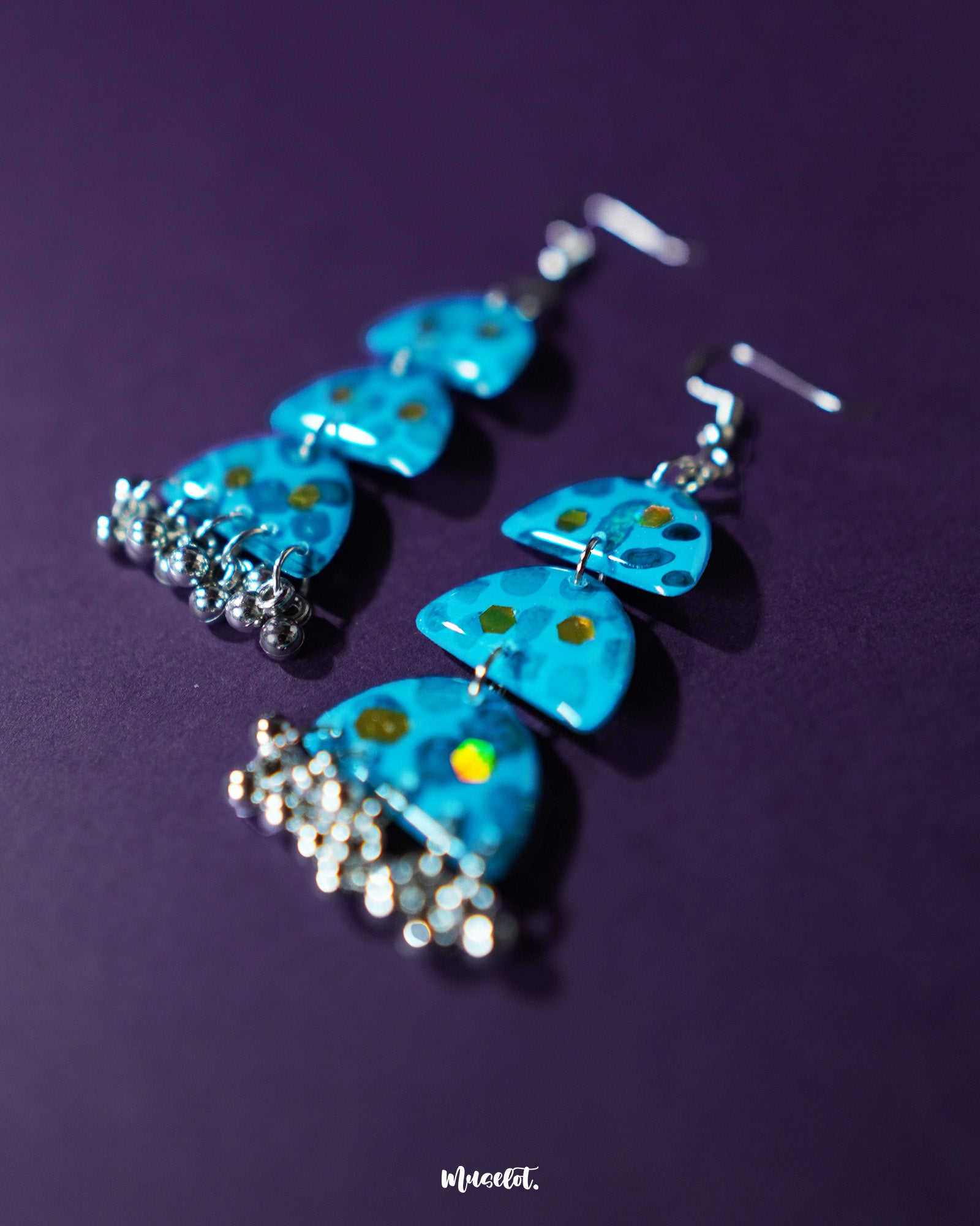 Close-up view of Parvaaz blue drop earrings featuring hand-painted blue flowers with delicate green leaves, highlighting their artistic finesse and showcasing a graceful blend of traditional and modern design — Muselot.