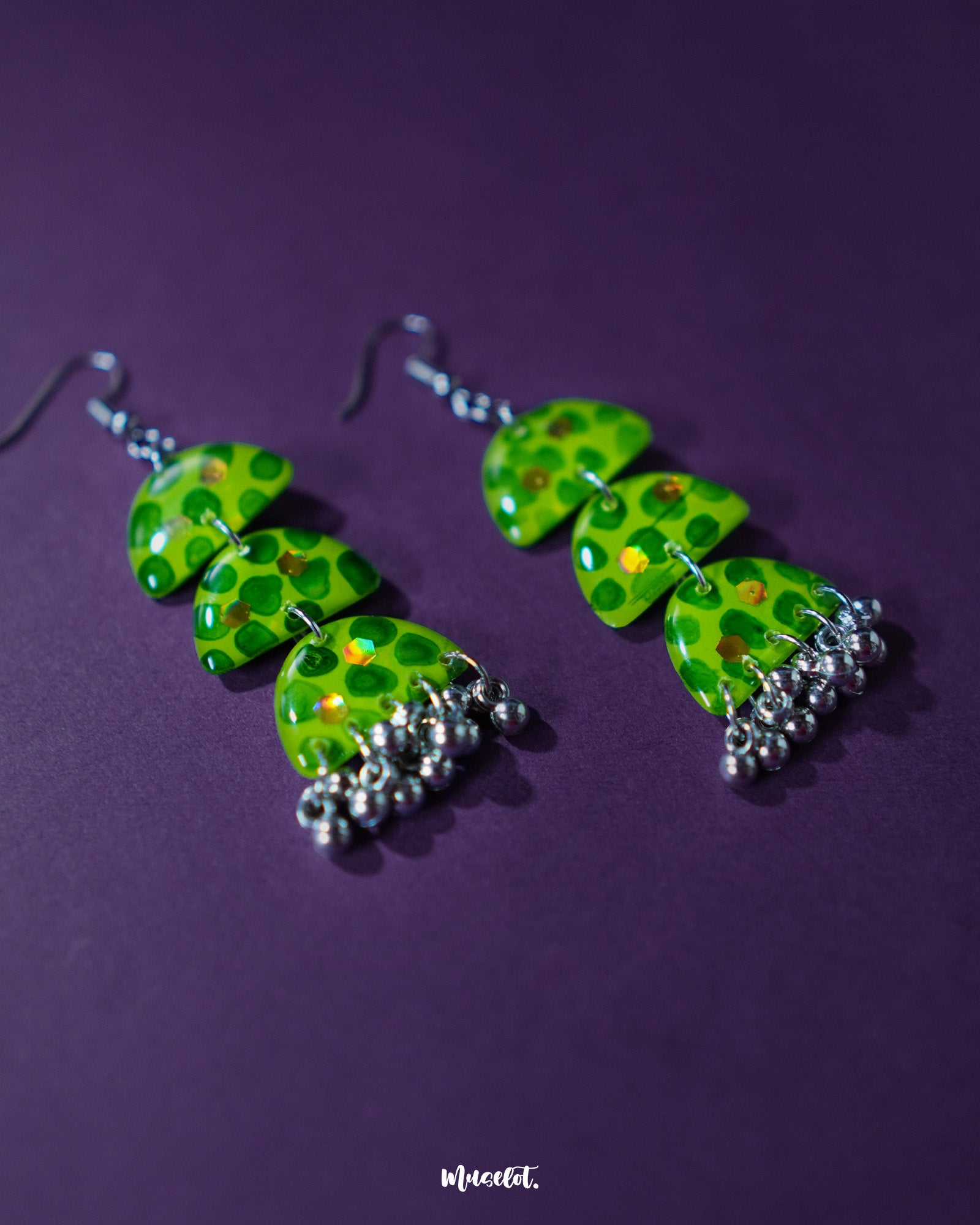 A close-up of Parvaaz green drop earrings, showing the teardrop shape with deep green dotted detailing over a soft light green base, highlighting the handcrafted texture and subtle artistic charm — Muselot.