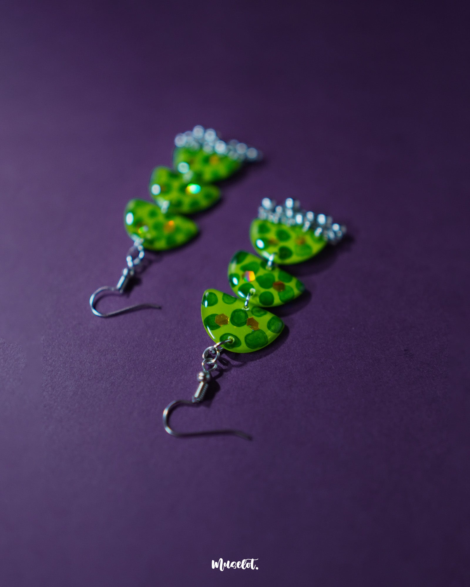 A close-up of Parvaaz green drop earrings featuring delicate dark green dot detailing on a rich green base, highlighting their earthy tones and minimalist handmade charm — Muselot.