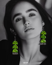 A woman wears the Parvaaz handmade green drop earrings, flaunting their tiered semicircle silhouette and dotted leafy design that highlights nature’s vibrancy and showcases a playful, artisanal flair — Muselot.